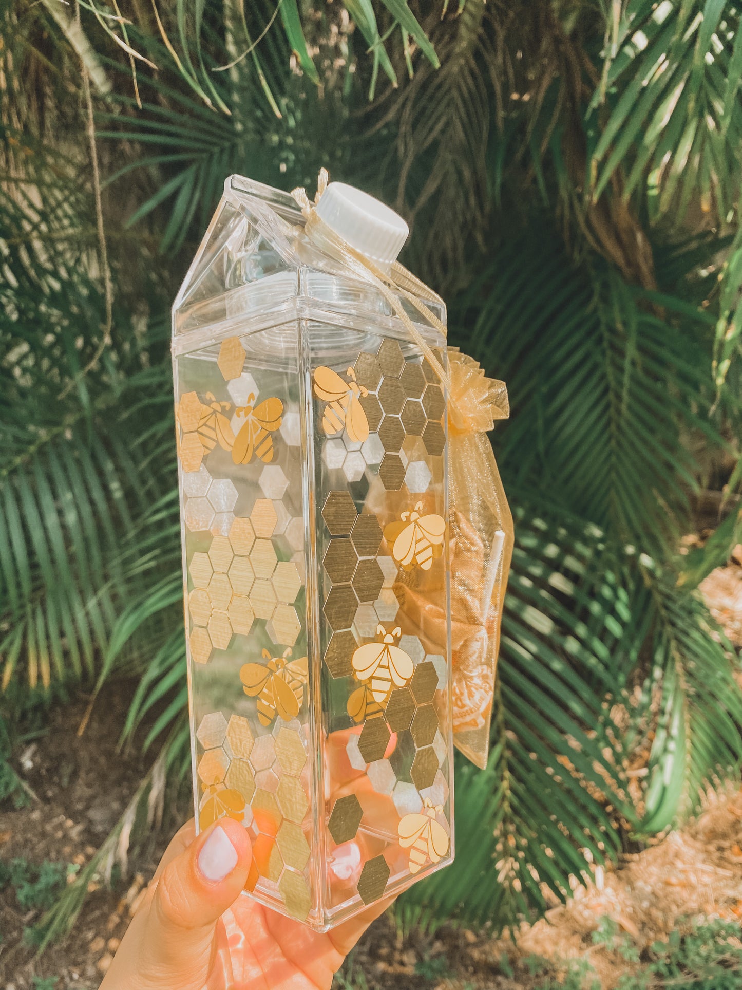 clear milk carton with gold honeycomb and yellow bees
